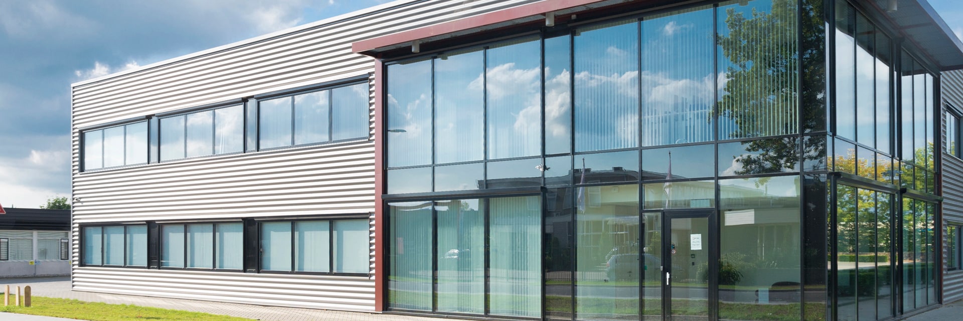 Modern kantoorgebouw met glazen façade weerspiegelt blauwe lucht.