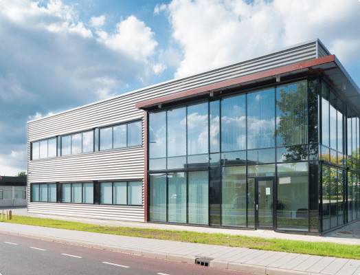 Modern kantoorgebouw met glazen façade weerspiegelt blauwe lucht.